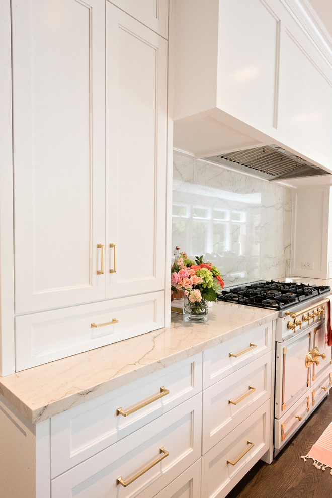 Open concept kitchen - large transitional l-shaped medium tone wood floor and brown floor open concept kitchen idea with a farmhouse sink, recessed-panel cabinets, white cabinets, quartzite countertops, white backsplash, stone slab backsplash, paneled appliances and an island