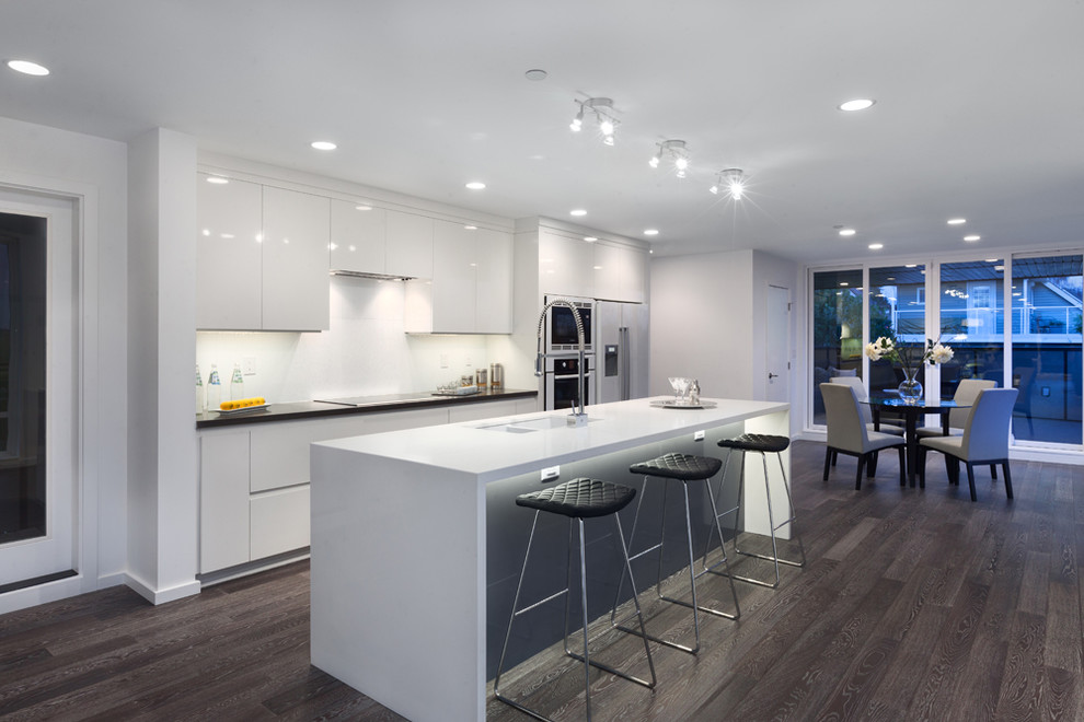 Design ideas for a modern galley eat-in kitchen in Vancouver with an undermount sink, flat-panel cabinets, white cabinets, white appliances and brown floor.