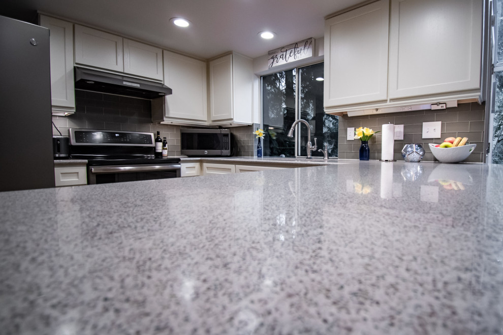 Inspiration for a transitional u-shaped medium tone wood floor open concept kitchen remodel in Seattle with an undermount sink, shaker cabinets, white cabinets, quartz countertops, gray backsplash, glass tile backsplash, stainless steel appliances, a peninsula and multicolored countertops