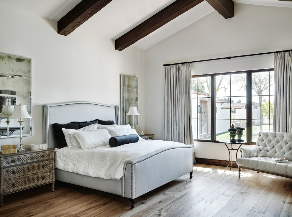 Photo of a large mediterranean master bedroom in Phoenix with white walls and medium hardwood floors.