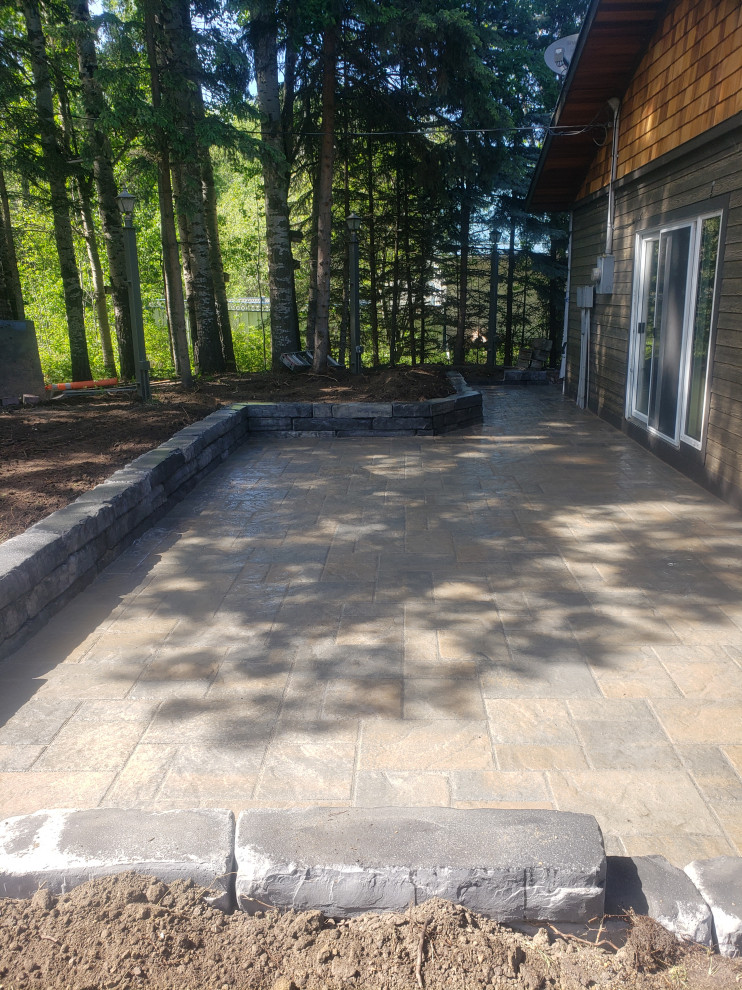Photo of a mid-sized rustic partial sun front yard concrete paver retaining wall landscape in Edmonton for summer.