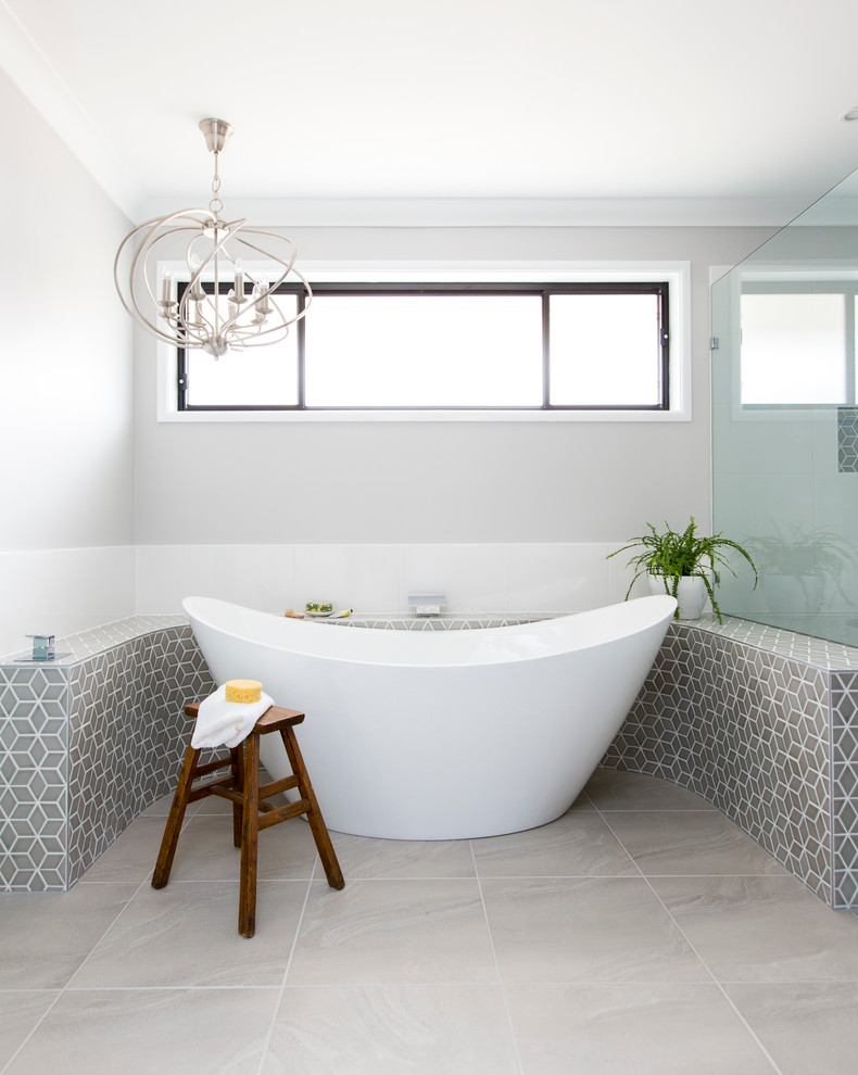 Design ideas for a large contemporary master bathroom in Brisbane with recessed-panel cabinets, grey cabinets, a freestanding tub, gray tile and grey walls.