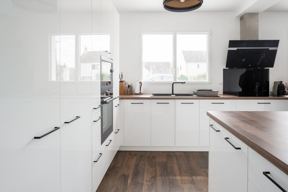 This is an example of a large modern u-shaped open plan kitchen in Paris with a submerged sink, white cabinets, wood worktops, white splashback, integrated appliances, dark hardwood flooring, an island, brown floors, brown worktops and exposed beams.
