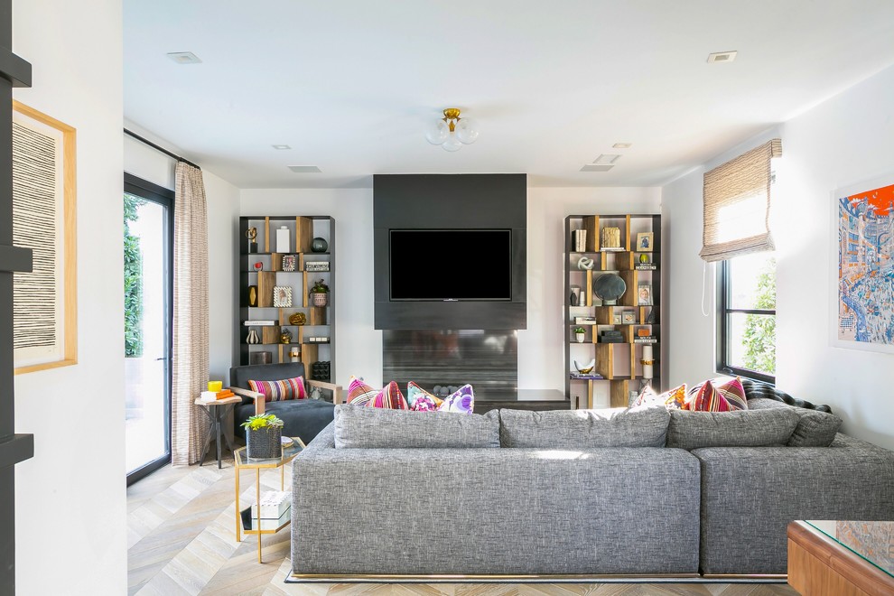 This is an example of a contemporary open concept family room in Orange County with white walls, medium hardwood floors, a wall-mounted tv and brown floor.