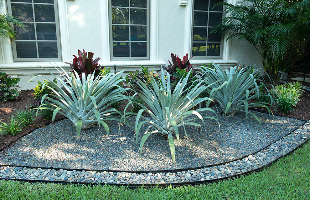 Large tropical front yard partial sun garden in Miami with a container garden and brick pavers.