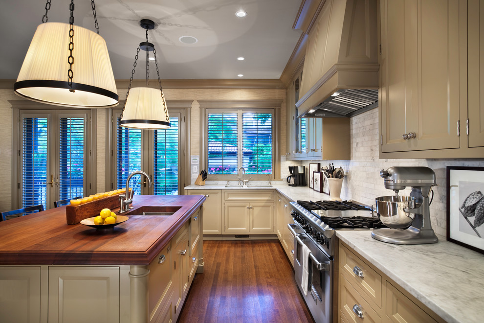 Inspiration for a traditional kitchen in Chicago with recessed-panel cabinets, stainless steel appliances, wood benchtops, beige cabinets and stone tile splashback.