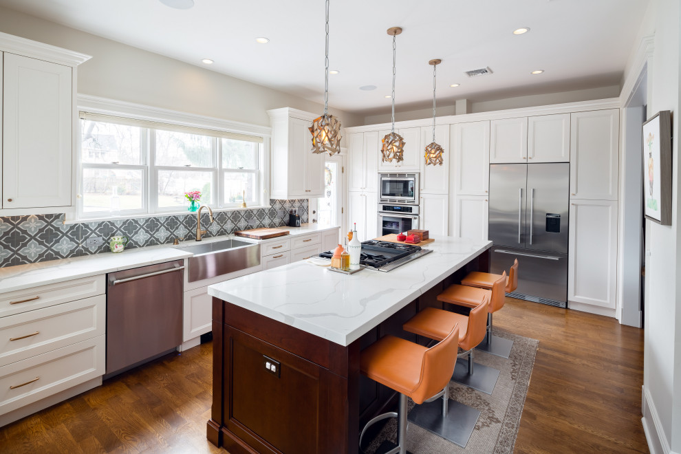 Kitchen - transitional l-shaped dark wood floor and brown floor kitchen idea in Newark with a farmhouse sink, recessed-panel cabinets, white cabinets, stainless steel appliances, an island and white countertops