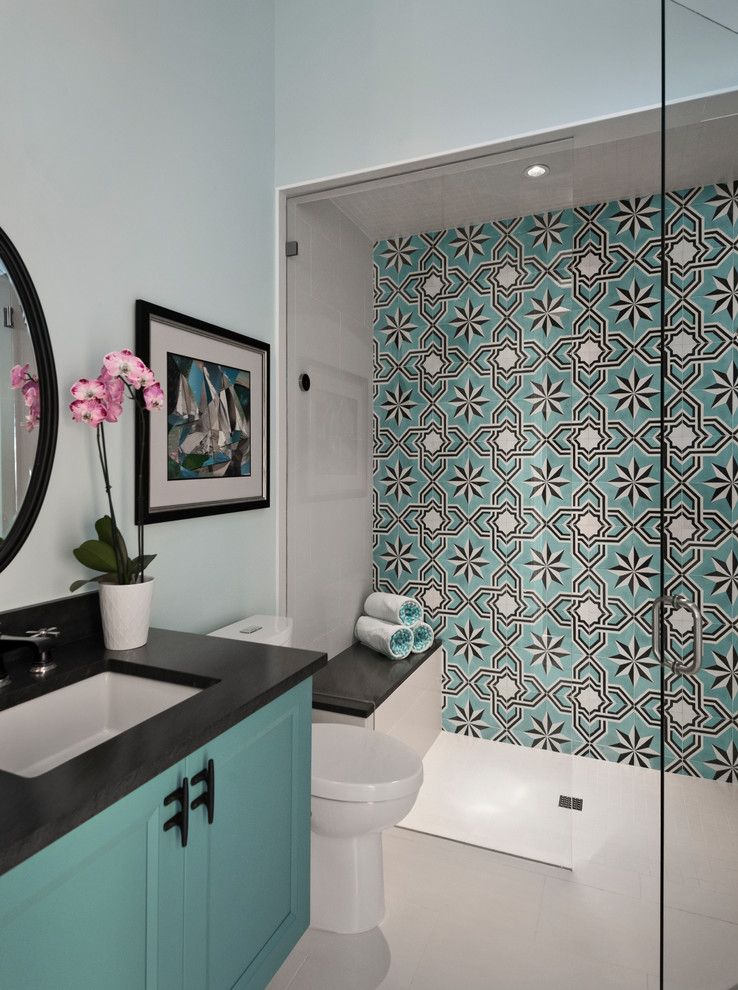 This is an example of a mid-sized transitional 3/4 bathroom in Other with shaker cabinets, blue cabinets, a curbless shower, multi-coloured tile, white walls, an undermount sink, white floor, an open shower, black benchtops, a two-piece toilet, cement tile, porcelain floors and granite benchtops.