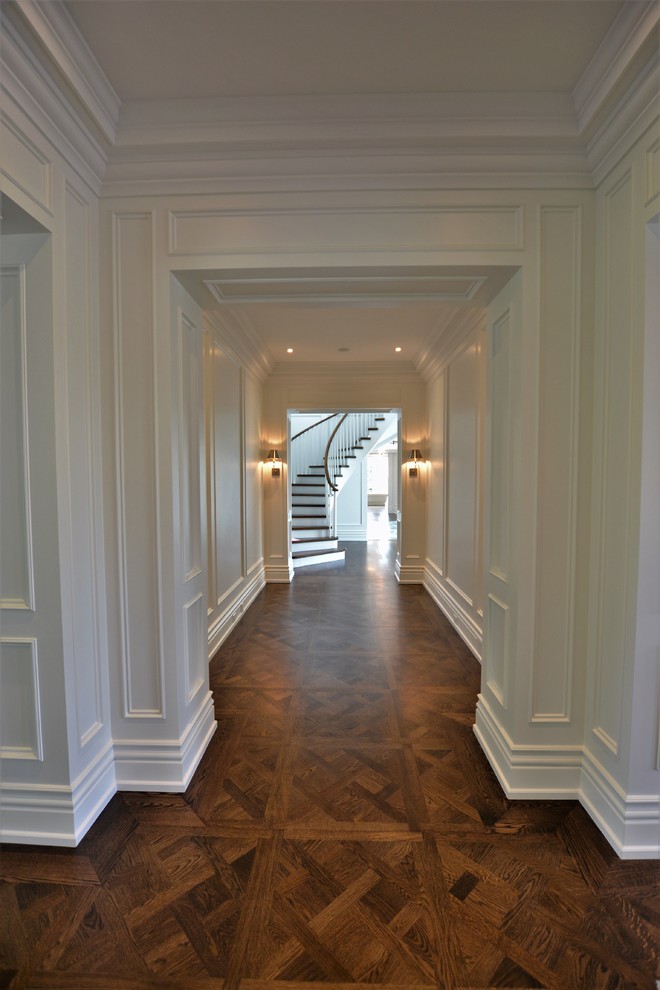This is an example of a mid-sized traditional hallway in Toronto with white walls, dark hardwood floors and brown floor.
