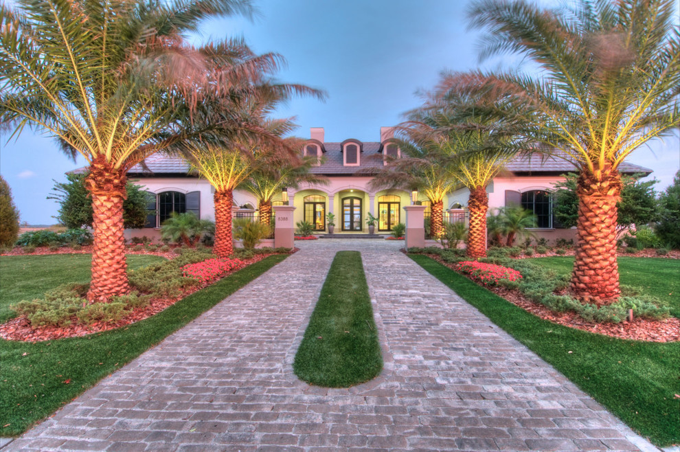 Design ideas for a tropical front yard driveway in Tampa with brick pavers.