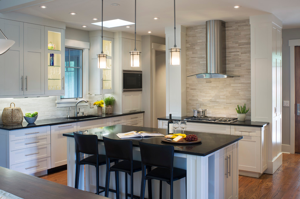 Photo of a transitional kitchen in Other with a single-bowl sink, shaker cabinets, white cabinets, granite benchtops, grey splashback, stainless steel appliances, medium hardwood floors, with island and limestone splashback.