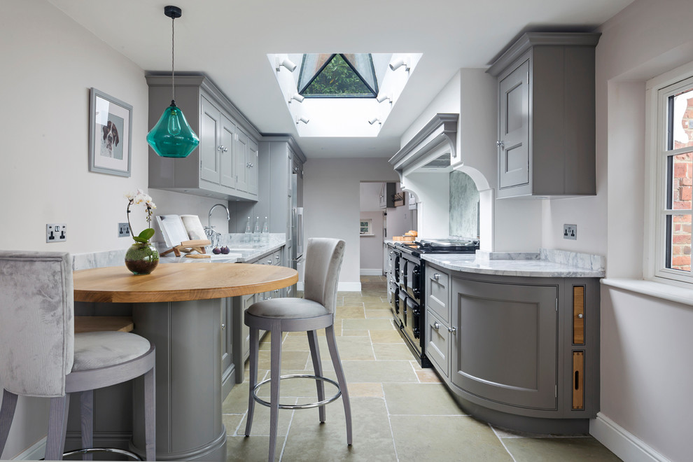 Inspiration for a small traditional galley eat-in kitchen in Hampshire with a double-bowl sink, flat-panel cabinets, grey cabinets, marble benchtops, mirror splashback, stainless steel appliances, limestone floors, no island and beige floor.