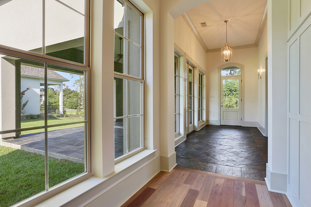 Entry hall - mid-sized rustic light wood floor entry hall idea in New Orleans with white walls and a white front door