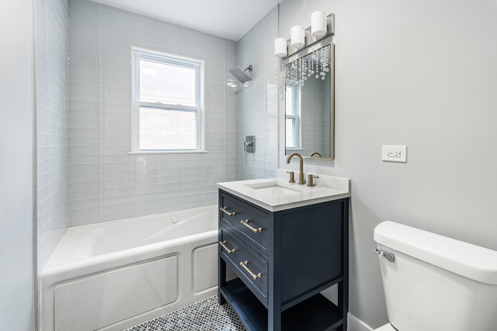 На фото: маленькая главная ванная комната в стиле модернизм с фасадами с выступающей филенкой, синими фасадами, отдельно стоящей ванной, раздельным унитазом, белой плиткой, стеклянной плиткой, серыми стенами, полом из мозаичной плитки, врезной раковиной, столешницей из искусственного кварца, синим полом, белой столешницей, тумбой под одну раковину и напольной тумбой для на участке и в саду с