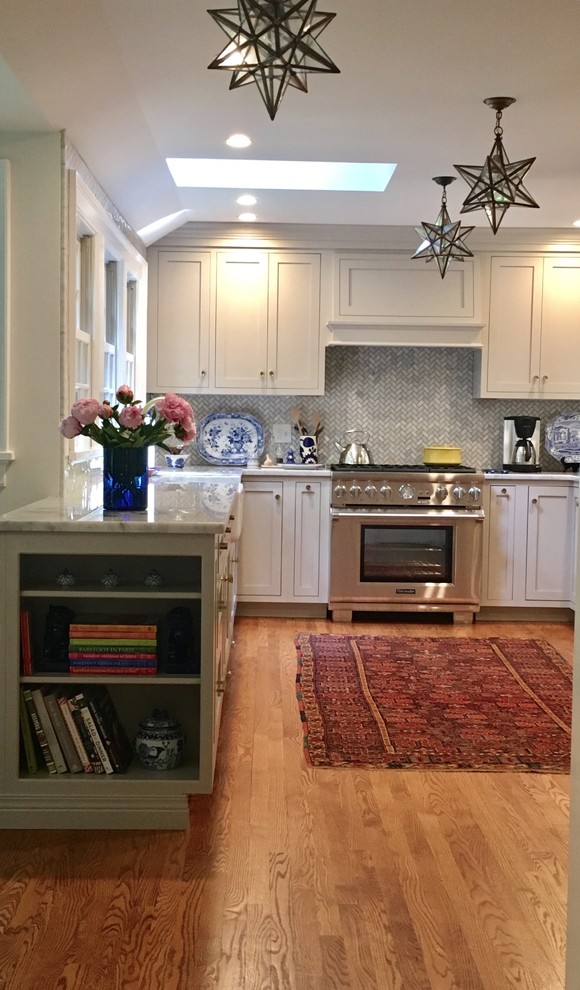 Mid-sized transitional u-shaped light wood floor and beige floor open concept kitchen photo in New York with a farmhouse sink, shaker cabinets, white cabinets, marble countertops, gray backsplash, marble backsplash and stainless steel appliances