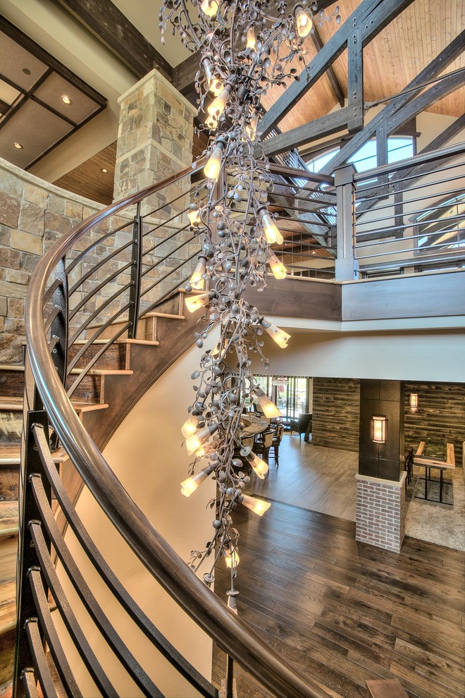 Huge mountain style wooden spiral staircase photo in Denver with wooden risers