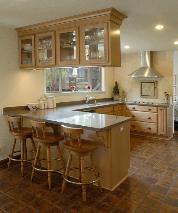 This is an example of a mid-sized traditional u-shaped eat-in kitchen in Sacramento with an undermount sink, raised-panel cabinets, light wood cabinets, quartzite benchtops, grey splashback, stone slab splashback, stainless steel appliances, terra-cotta floors and no island.