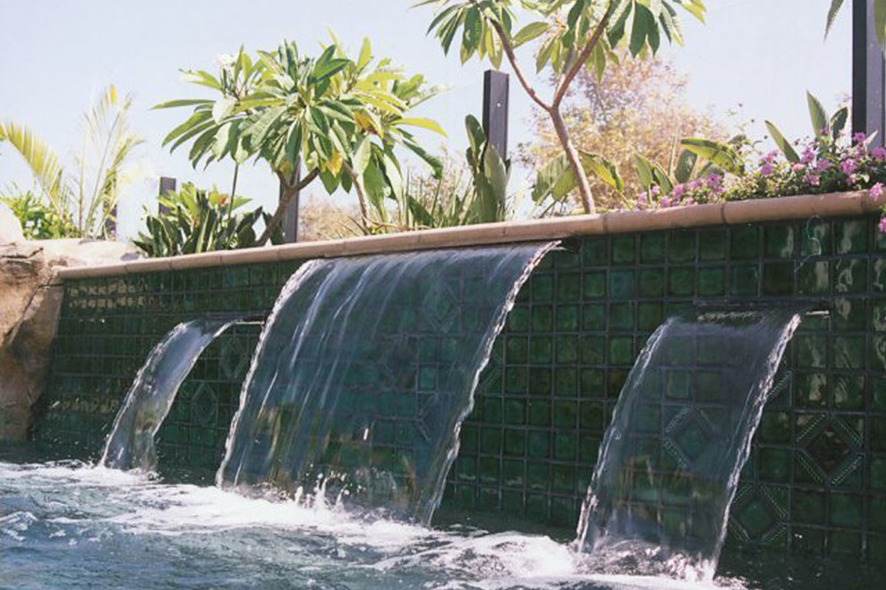 Inspiration for a mid-sized traditional backyard lap pool in Orange County with a water feature and natural stone pavers.