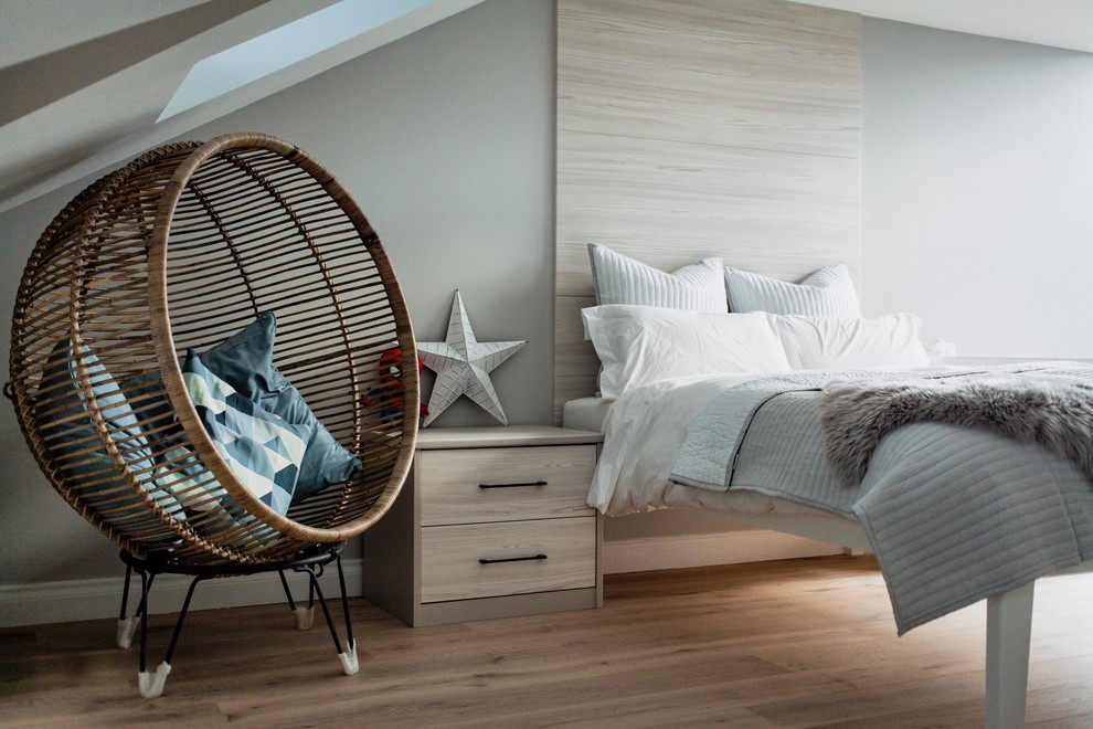 This is an example of a scandinavian gender-neutral kids' bedroom for kids 4-10 years old in London with blue walls, medium hardwood floors and brown floor.