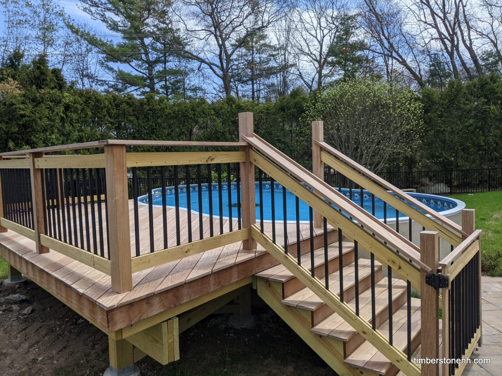 Design ideas for a small backyard and ground level deck in Manchester with mixed railing.