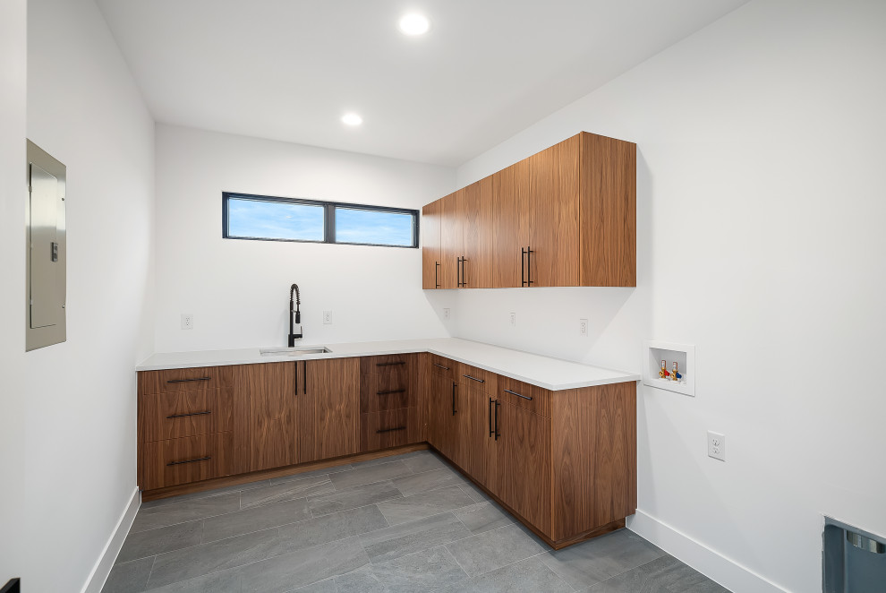 This is an example of a large midcentury dedicated laundry room in Denver with an undermount sink, flat-panel cabinets, dark wood cabinets, quartz benchtops, white walls, slate floors, a side-by-side washer and dryer, grey floor and white benchtop.