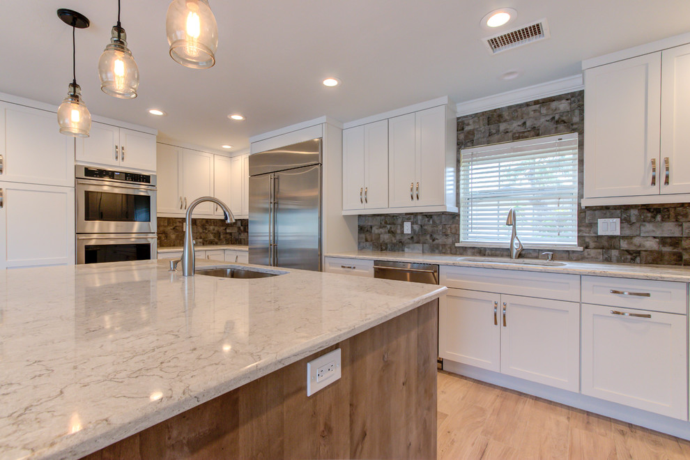 Inspiration for a large transitional u-shaped porcelain tile and brown floor enclosed kitchen remodel with an undermount sink, shaker cabinets, white cabinets, quartz countertops, brown backsplash, stainless steel appliances, an island and beige countertops