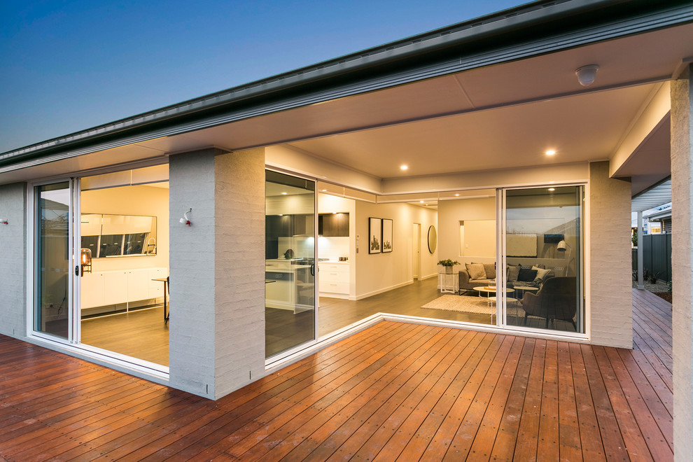This is an example of a mid-sized contemporary one-storey stucco beige house exterior in Sydney with a metal roof.