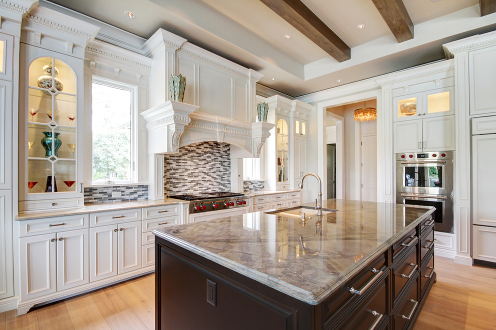 Inspiration for a large transitional u-shaped brown floor and light wood floor kitchen remodel in Miami with an undermount sink, recessed-panel cabinets, white cabinets, multicolored backsplash, glass tile backsplash, paneled appliances, two islands and quartzite countertops