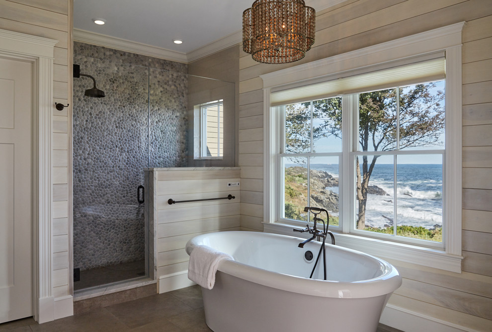 Inspiration for a beach style master bathroom in Portland Maine with a freestanding tub, an alcove shower, multi-coloured tile, pebble tile, beige walls, brown floor and a hinged shower door.