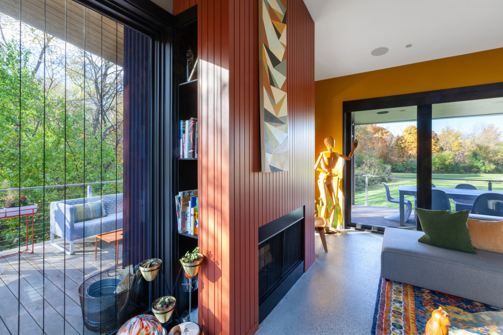 Mittelgroßes, Offenes Modernes Wohnzimmer mit gelber Wandfarbe, Betonboden, Kamin, Kaminumrandung aus Holz, TV-Wand, grauem Boden und gewölbter Decke in Indianapolis