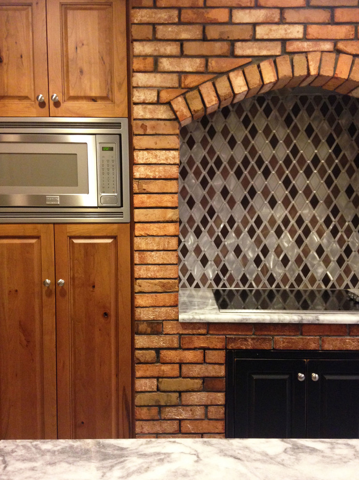 Large mountain style l-shaped ceramic tile and gray floor eat-in kitchen photo in New York with raised-panel cabinets, distressed cabinets, granite countertops, an island, an undermount sink, gray backsplash, ceramic backsplash and stainless steel appliances