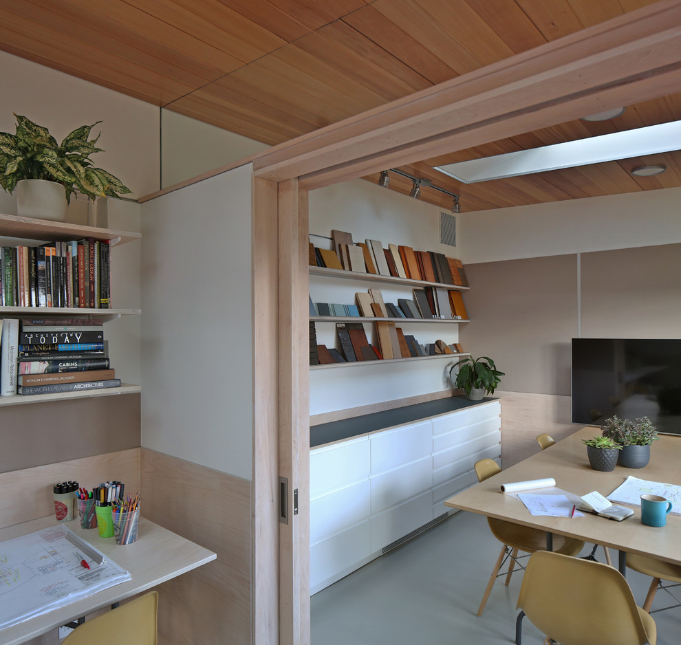 This is an example of a mid-sized modern home studio in Seattle with white walls, concrete floors, a freestanding desk and grey floor.