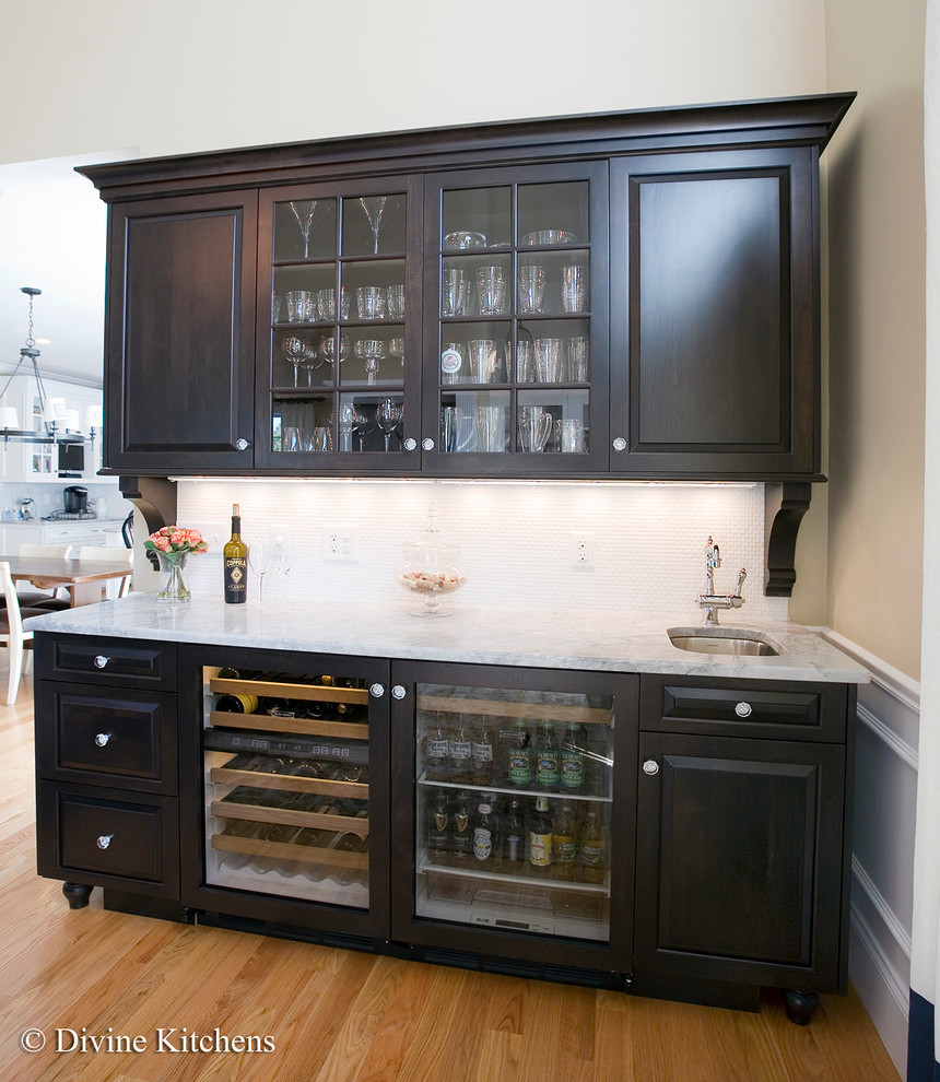 Large traditional galley home bar in Boston with beaded inset cabinets, yellow cabinets, granite benchtops, white splashback and light hardwood floors.