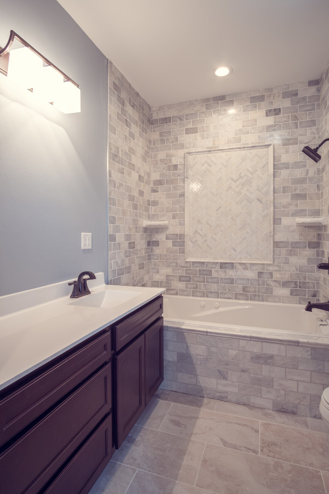 Design ideas for a mid-sized transitional master bathroom in Boise with raised-panel cabinets, brown cabinets, a corner tub, a shower/bathtub combo, gray tile, stone tile, grey walls, ceramic floors, a drop-in sink and granite benchtops.