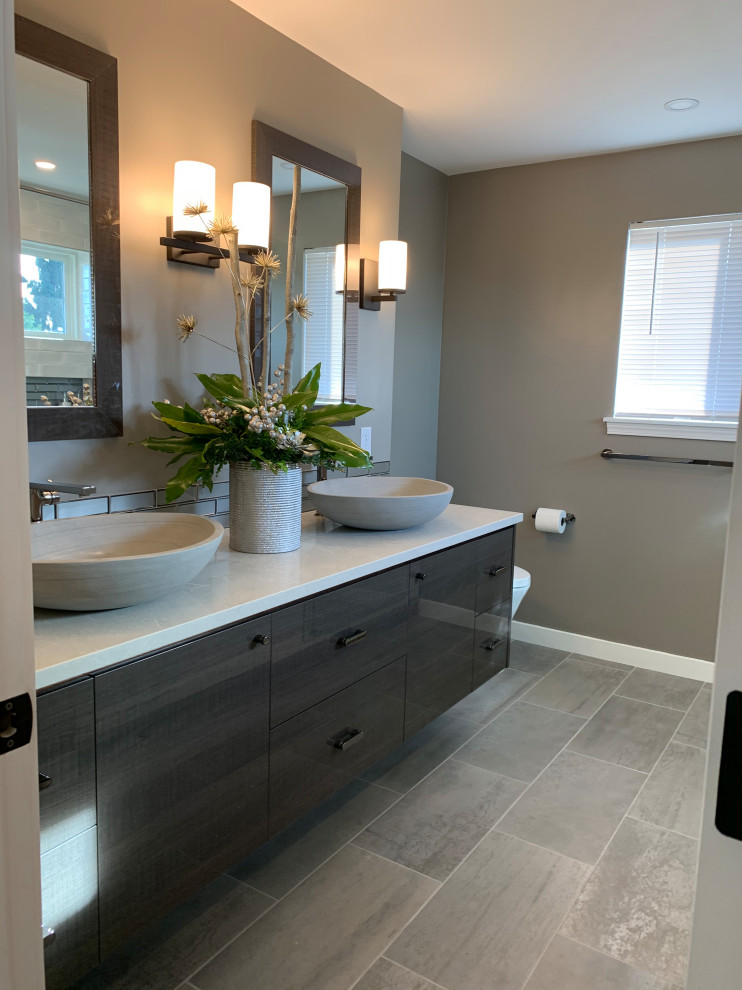 Photo of a mid-sized modern master bathroom with flat-panel cabinets, black cabinets, an alcove shower, a two-piece toilet, gray tile, glass tile, grey walls, wood-look tile, a vessel sink, engineered quartz benchtops, grey floor, a sliding shower screen, white benchtops, a niche, a shower seat, a double vanity and a floating vanity.