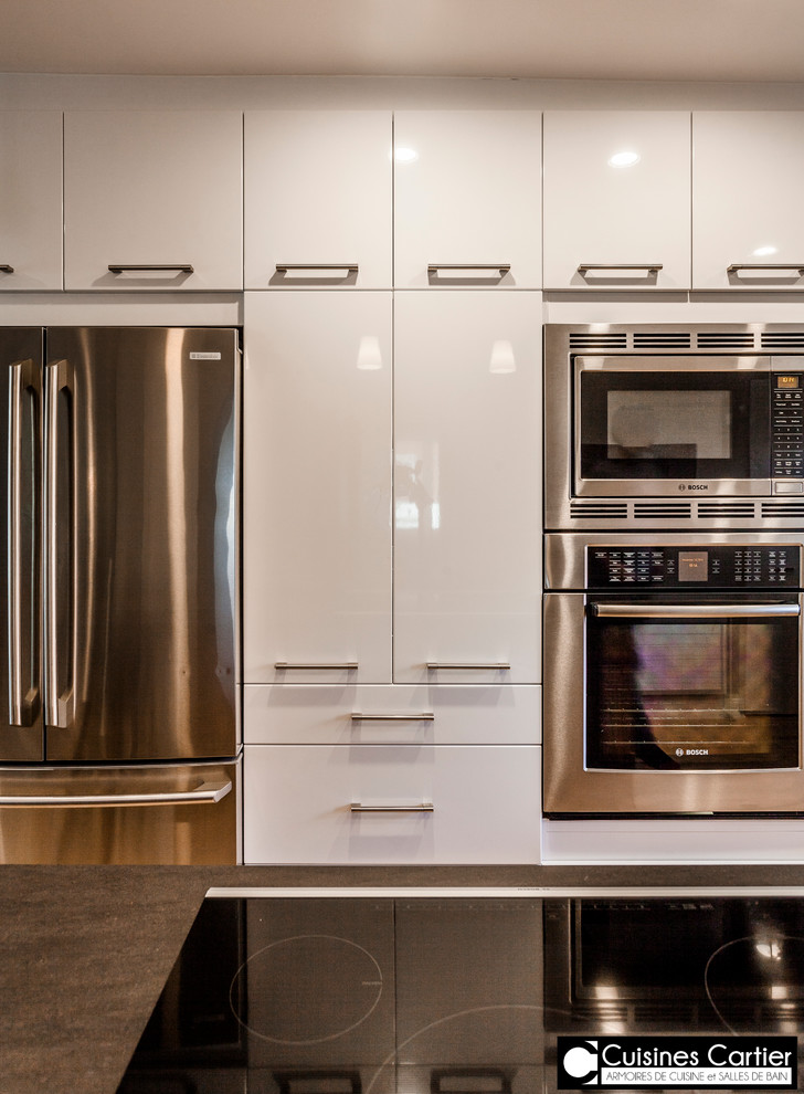Eat-in kitchen - large transitional galley medium tone wood floor eat-in kitchen idea in Montreal with an undermount sink, flat-panel cabinets, dark wood cabinets, quartzite countertops, white backsplash, mosaic tile backsplash, stainless steel appliances and an island