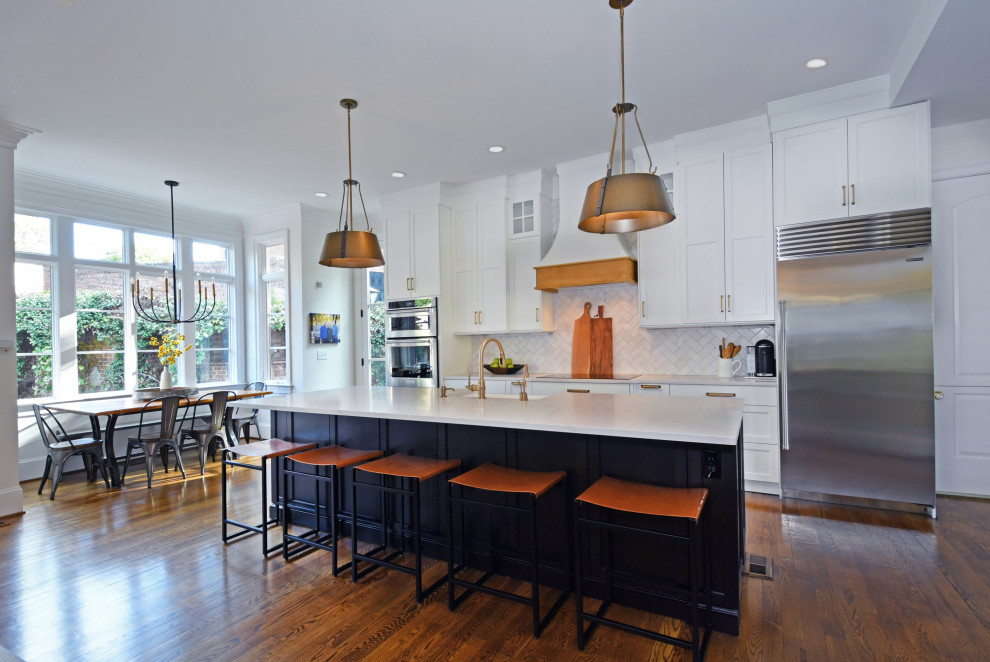 Kitchen pantry - large transitional galley medium tone wood floor and brown floor kitchen pantry idea with a farmhouse sink, recessed-panel cabinets, white cabinets, quartz countertops, white backsplash, marble backsplash, stainless steel appliances, an island and white countertops