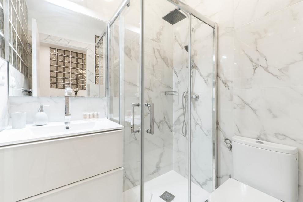 Small trendy master white tile and marble tile marble floor, white floor and single-sink bathroom photo in Tampa with flat-panel cabinets, white cabinets, a one-piece toilet, white walls, an integrated sink, solid surface countertops, white countertops and a floating vanity