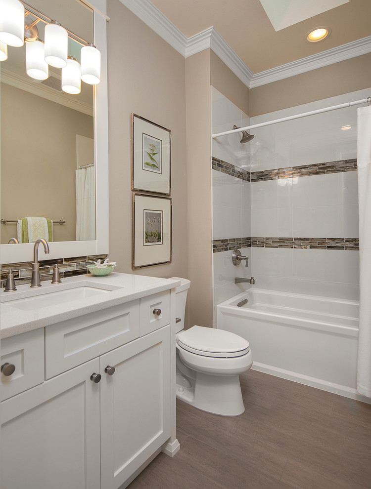 Design ideas for a small transitional 3/4 bathroom in Seattle with shaker cabinets, white cabinets, an alcove tub, a shower/bathtub combo, a one-piece toilet, white tile, beige walls, medium hardwood floors, an undermount sink, engineered quartz benchtops, brown floor, a shower curtain and white benchtops.