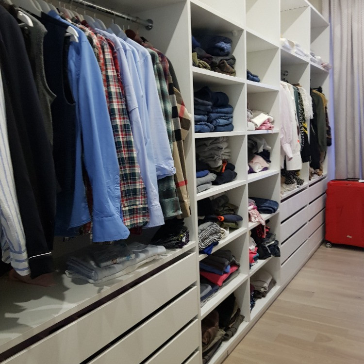 This is an example of a medium sized traditional gender neutral walk-in wardrobe in Moscow with flat-panel cabinets, white cabinets, laminate floors and beige floors.