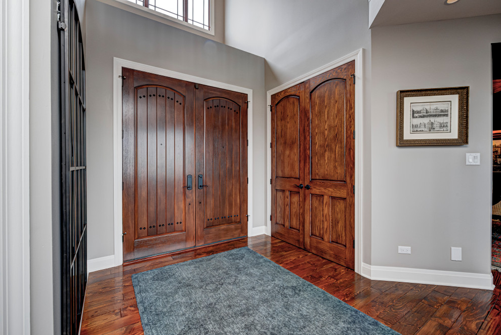 Aménagement d'une porte d'entrée éclectique de taille moyenne avec un mur gris, une porte double, parquet foncé, une porte en bois foncé et un sol marron.