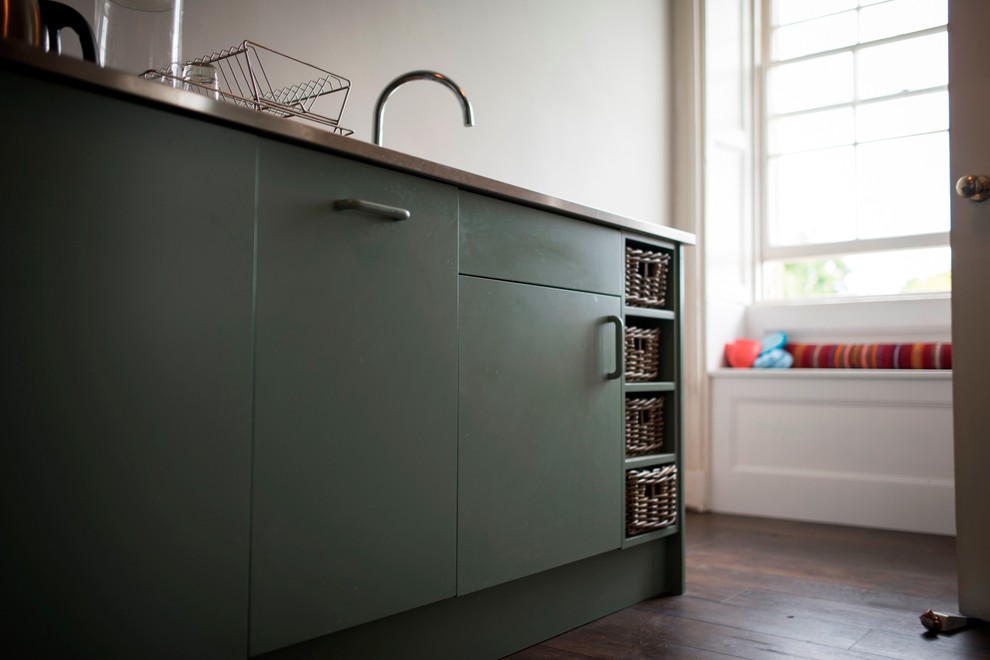 Small contemporary galley separate kitchen in Wiltshire with a drop-in sink, flat-panel cabinets, green cabinets, stainless steel benchtops, metallic splashback, metal splashback, stainless steel appliances, no island and medium hardwood floors.