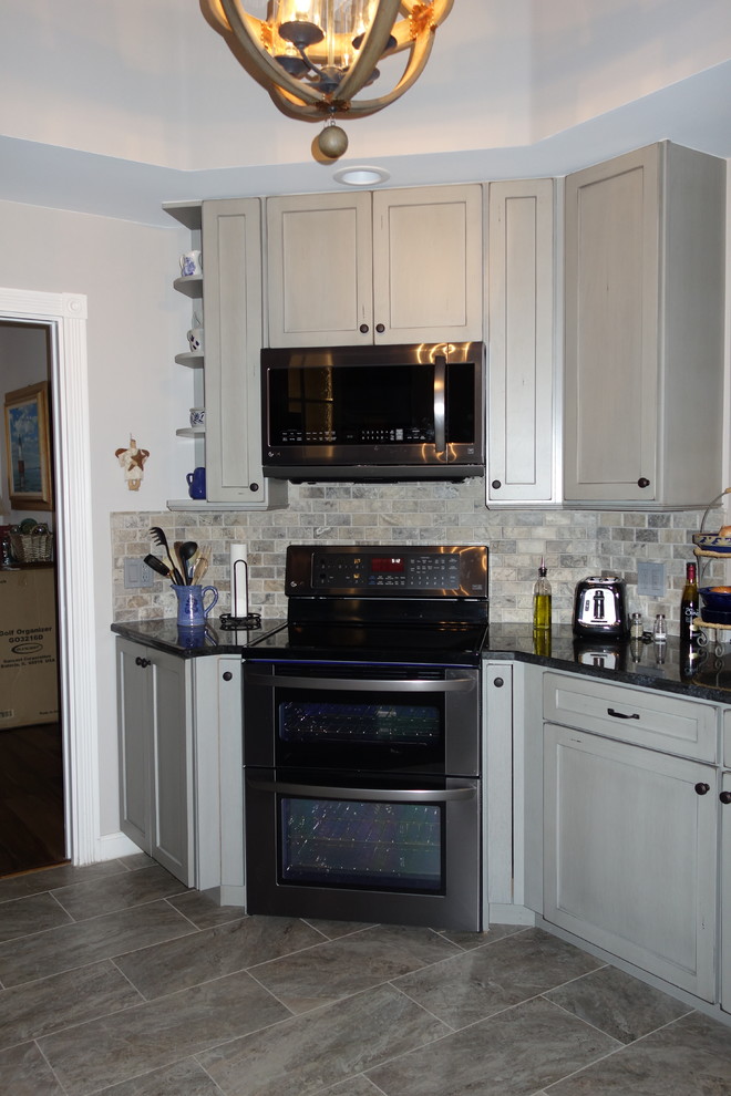 Open concept kitchen - mid-sized transitional ceramic tile open concept kitchen idea in Miami with an undermount sink, flat-panel cabinets, gray cabinets, granite countertops, gray backsplash, stone tile backsplash and stainless steel appliances