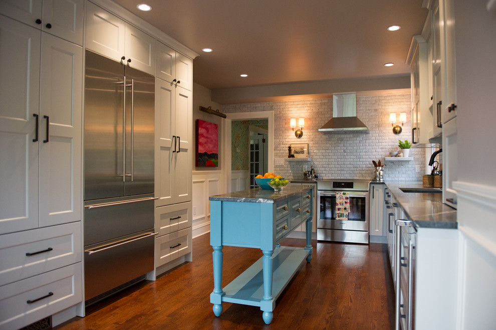 Mid-sized transitional l-shaped dark wood floor eat-in kitchen photo with an undermount sink, soapstone countertops, gray backsplash, stone tile backsplash, stainless steel appliances, an island, shaker cabinets and white cabinets