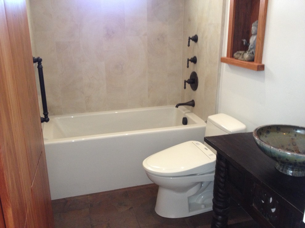 Design ideas for an asian bathroom in San Francisco with a bidet, a vessel sink, an alcove tub, a shower/bathtub combo, furniture-like cabinets, dark wood cabinets, wood benchtops and stone tile.