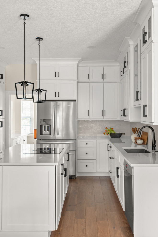 Kitchen - transitional brown floor kitchen idea in Orlando with quartzite countertops, white backsplash, ceramic backsplash, stainless steel appliances, an island and white countertops
