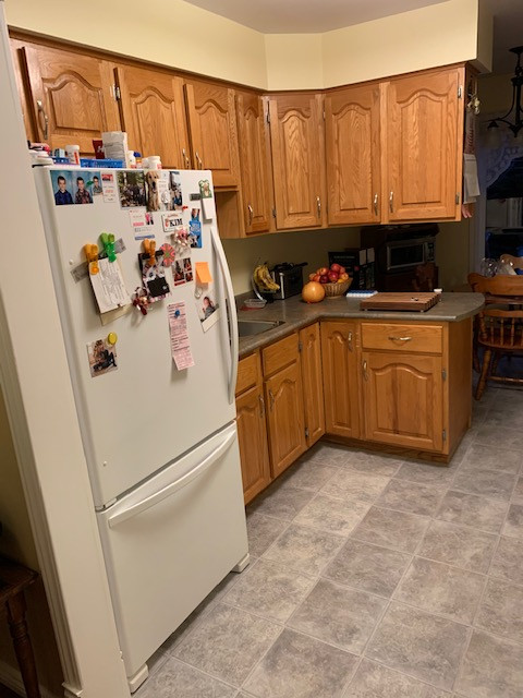 Example of a mid-sized transitional galley enclosed kitchen design with a drop-in sink, raised-panel cabinets, medium tone wood cabinets, laminate countertops, white appliances, a peninsula and gray countertops