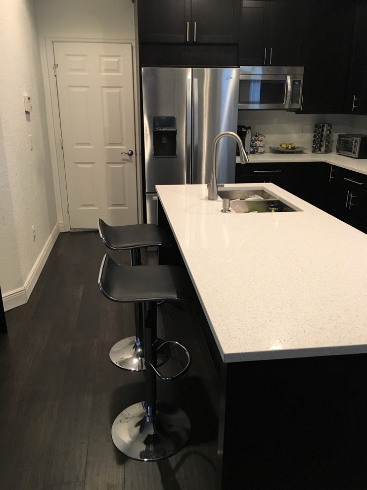 Example of a minimalist kitchen design in Orlando with quartz countertops, stainless steel appliances and an island