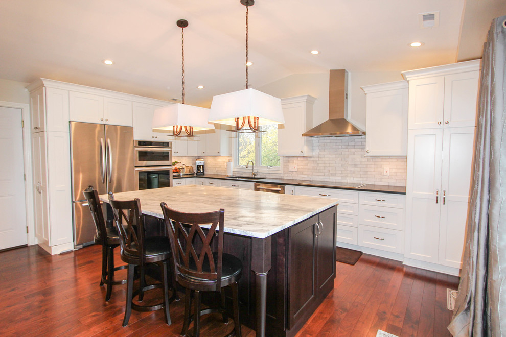 Example of a mid-sized transitional l-shaped medium tone wood floor eat-in kitchen design in Cincinnati with an undermount sink, recessed-panel cabinets, white cabinets, quartzite countertops, white backsplash, subway tile backsplash, stainless steel appliances and an island
