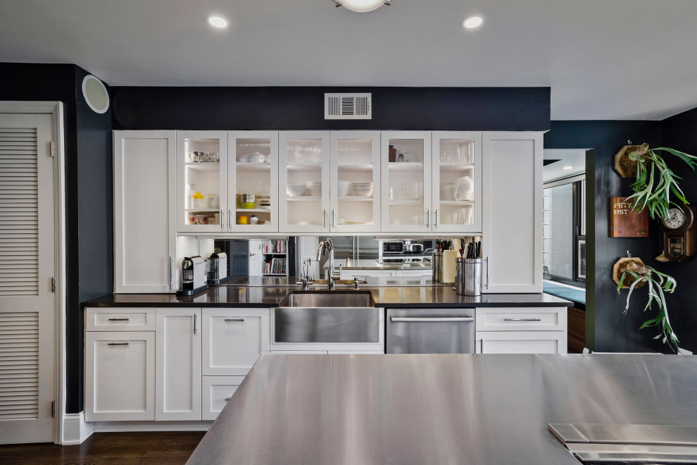 Inspiration for a large midcentury kitchen in Chicago with a farmhouse sink, glass-front cabinets, white cabinets, metallic splashback, mirror splashback, stainless steel appliances, dark hardwood floors, with island and grey benchtop.